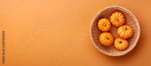 Basket of small Halloween pumpkins on a vibrant orange background for creative text placement and seasonal decoration ideas photo