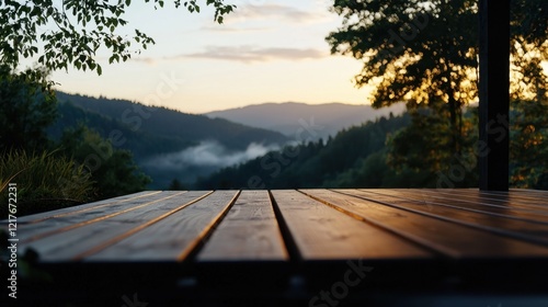 A tranquil landscape unfolds with rolling mountains at sunset, framed by a wooden deck. Soft clouds linger in the valley, creating a serene atmosphere, perfect for relaxation