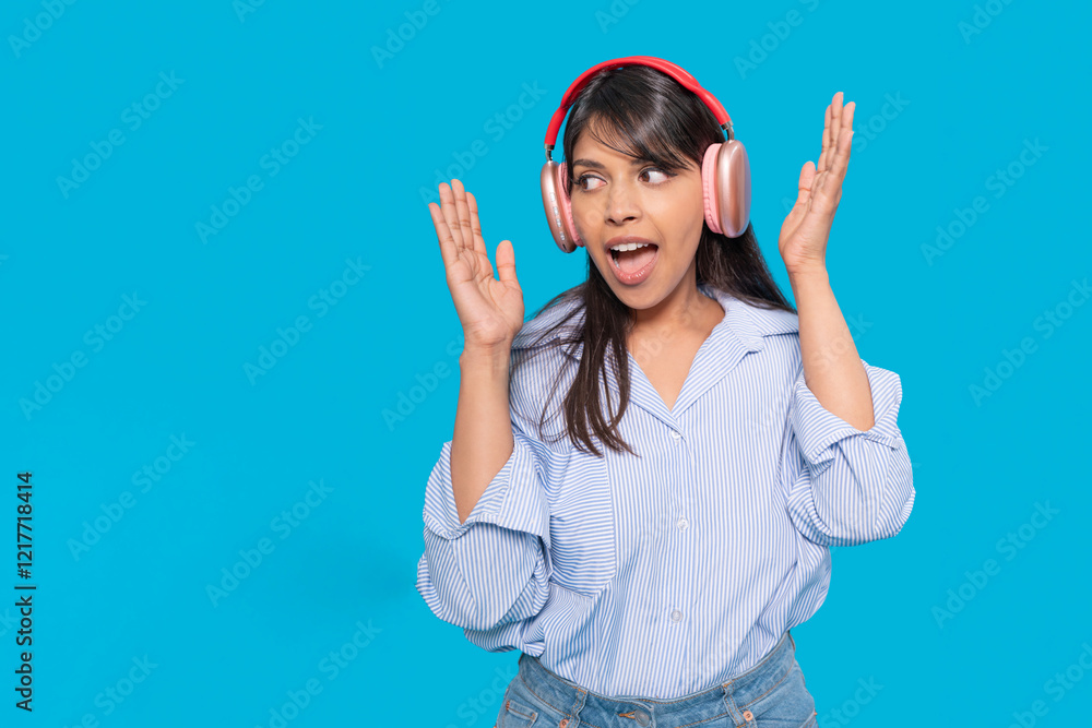 Fototapeta premium Woman enjoying music while dancing and smiling against a bright blue background