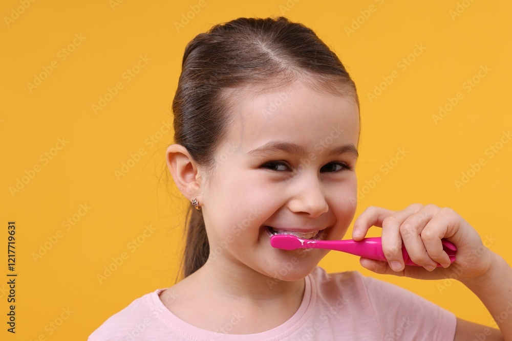 Cute girl brushing her teeth on orange background Cute girl brushing her teeth on orange background