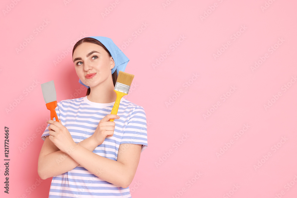 Portrait of young decorator with putty knife and brush on pink background, space for text Portrait of young decorator with putty knife and brush on pink background, space for text