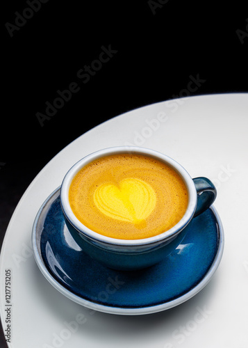 Coffee with orange juice in a blue cup on a white table. Bumble or capuorange decorated with latte art in the shape of a heart. Black background. Place for text. Menu for a cafe or restaurant. photo