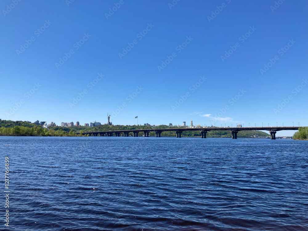 Panoramic photograph of a calm water body with a bridge, possibly a lake or sea near an urban area Clear sky above Panoramic photograph of a calm water body with a bridge, possibly a lake or sea near an urban area Clear sky above