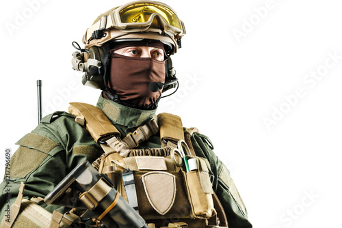 A heavily armed soldier in specialized tactical equipment looking forward, isolated on a white background for military or security-related themes photo