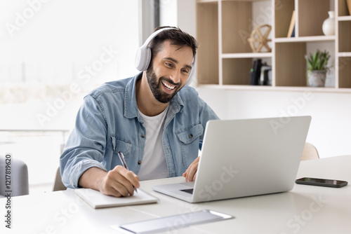 Smiling Hispanic man take part in online class using laptop and videocall application, enjoying remote communication with colleagues, e-learning, improving professional knowledges online. Education photo