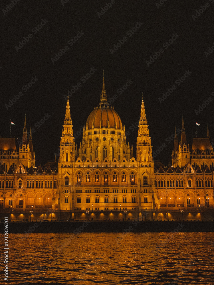 Obraz premium Beautiful photograph of the Hungarian Parliament Building in Budapest at night, illuminated against the dark sky.