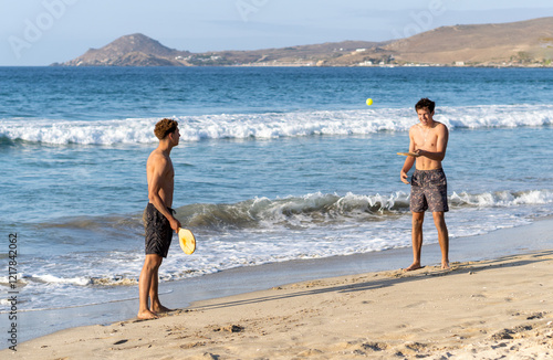 Obraz na płótnie Two young men playing paddle ball in the beach w salonie
