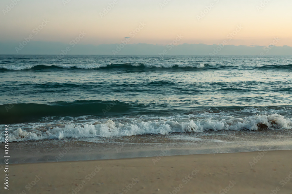 Tranquil ocean waves meet the shore at dusk.