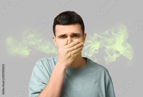 Фотография Handsome young man feeling bad smell on grey background