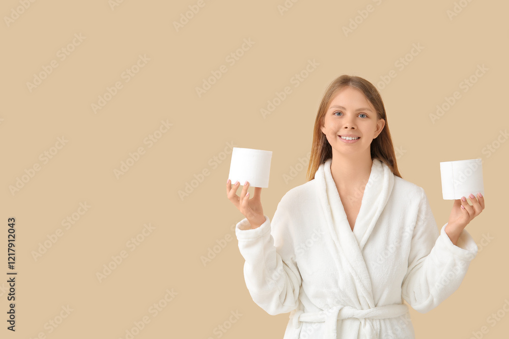 Young woman in bathrobe with toilet paper rolls on color background Young woman in bathrobe with toilet paper rolls on color background
