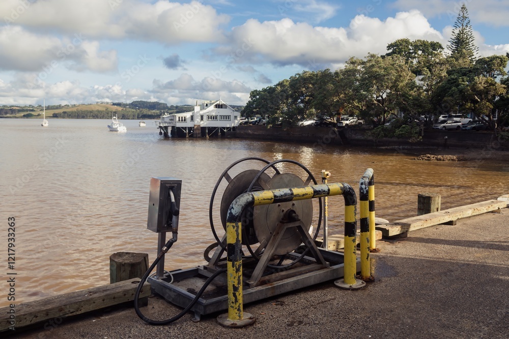Dockside equipment for boats, a fuel hose reel, and a fueling station. Sunny day at a waterfront restaurant. , Mangonui, Northland, NZ Dockside equipment for boats, a fuel hose reel, and a fueling station. Sunny day at a waterfront restaurant. , Mangonui, Northland, NZ