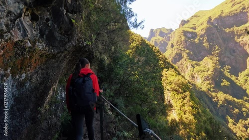 Active woman with backpacks hiking green forest trail path and climbing Madeira Island. Tourist woman enjoying summer vacation 