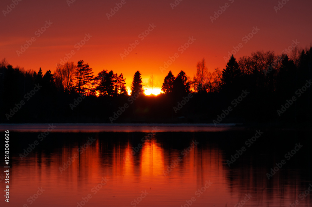 Naklejka premium Sunset colours reflected from a calm lake in spring in Western Finland