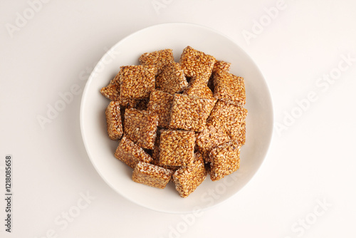 Sesame seed jaggery chikki or til ke chkki and tilgul or til gul ladduchikki served in bowl for Makar Sankranti Festival in India photo