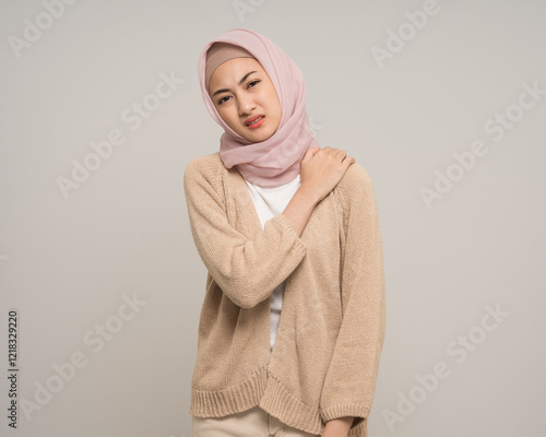 Unhappy young asian muslim woman has problem with structural posture neck and shoulder pain standing on isolated white background. Muslim woman wearing abaya and hijab has bad posture photo