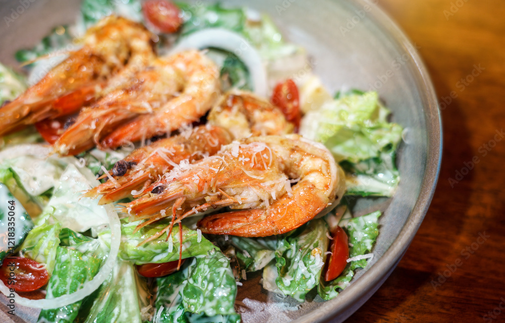 Caesar salad with Fried shrimp in a plate served ready to eat on a wooden table. Caesar salad with Fried shrimp in a plate served ready to eat on a wooden table.
