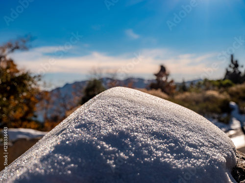 Close-up of snow pile with blue skies and landscape background  photo