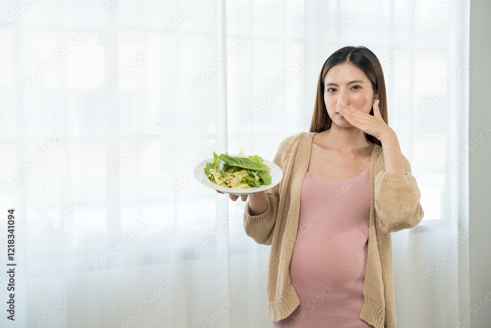 Unhappy young asian pregnant woman feeling with morning sickness to vegetable salad, frustrated young lady refusing eating vegetable, concept of hate vegetarian nutrition Unhappy young asian pregnant woman feeling with morning sickness to vegetable salad, frustrated young lady refusing eating vegetable, concept of hate vegetarian nutrition