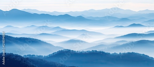 Blue misty mountain range with layered silhouettes under soft morning light, creating a serene pastel foggy atmosphere.