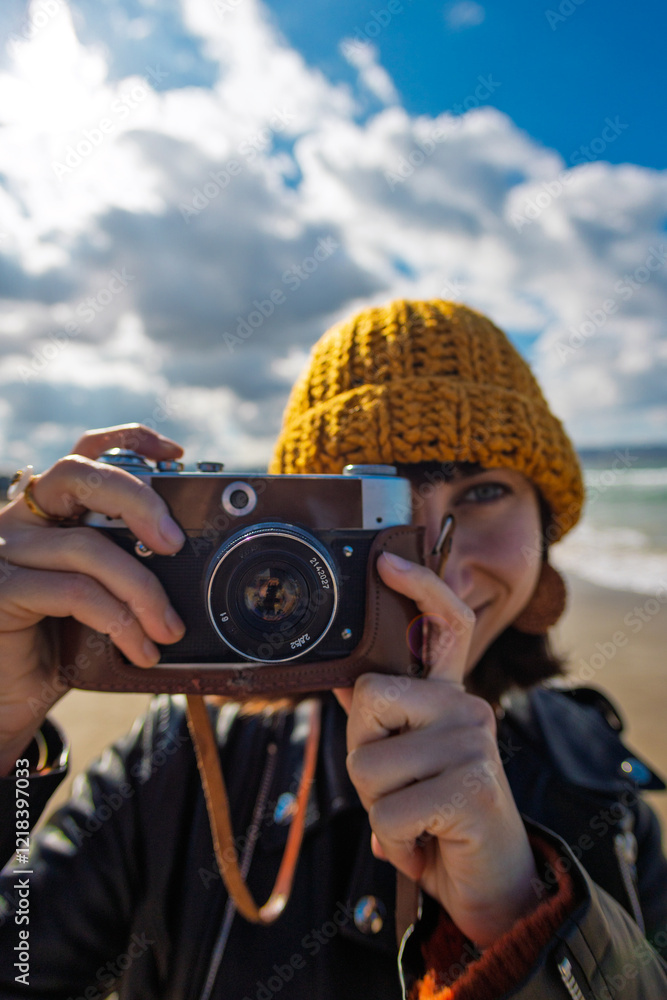 Obraz premium Woman taking photos outdoors. close-up of camera. Young beautiful girl creating content while walking on the beach.