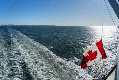 Ferry sailing on the ocean. Canadian flag and waves. Southern Gulf Islands, Strait of Georgia. photo