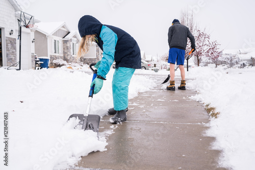 Father and child shovel snow from sidewalk in neighborhood