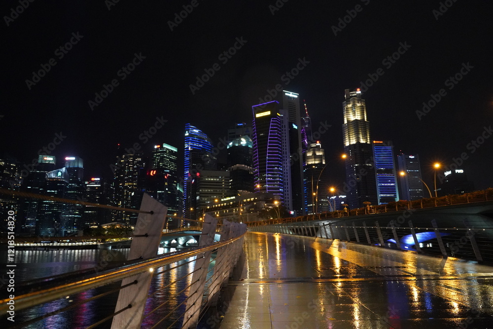 Fototapeta premium Marina Bay Sands lights up Singapore’s skyline at night with its glowing towers and rooftop, showcasing stunning modern architecture above the shimmering Marina Bay. 