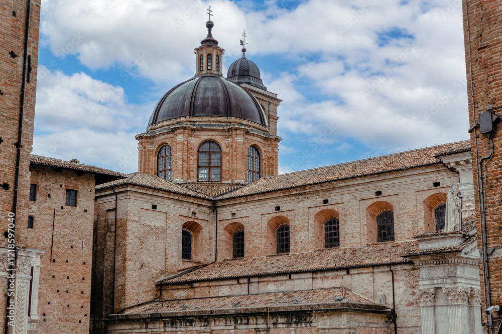 The Ducale Palace, an iconic symbol of Urbino, highlights intricate brickwork and elegant domes. This architectural marvel reflects the city's rich history. Urbino, Marche, Italy