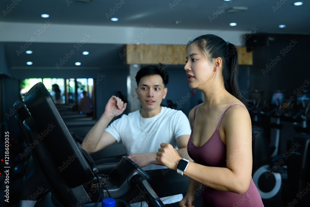 Active woman running on treadmill while fitness trainer providing encouragement and guidance Active woman running on treadmill while fitness trainer providing encouragement and guidance