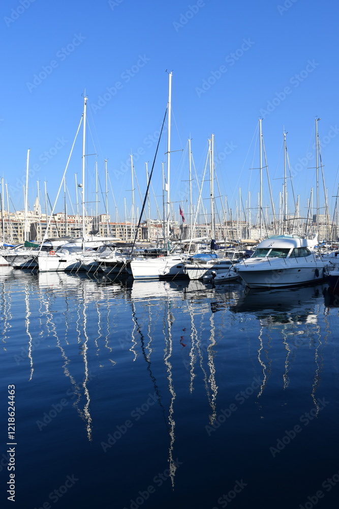 Obraz premium Boats docked in the Vieux-Port of Marseille, reflecting warm hues over the calm water. A picturesque scene showcasing the city's maritime charm.
