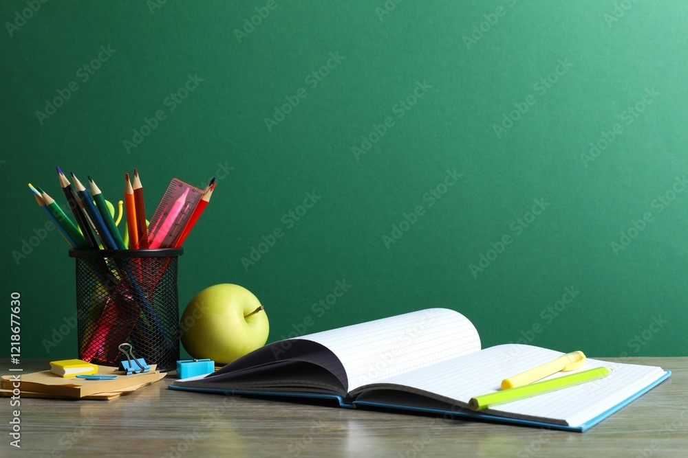 Back to school. Close-up of colorful stationery, textbooks, green apple on green chalkboard Back to school. Close-up of colorful stationery, textbooks, green apple on green chalkboard