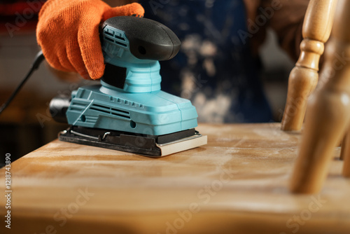 фотографія carpenter sanding polishing wooden chair with electric sander in his carpentry w