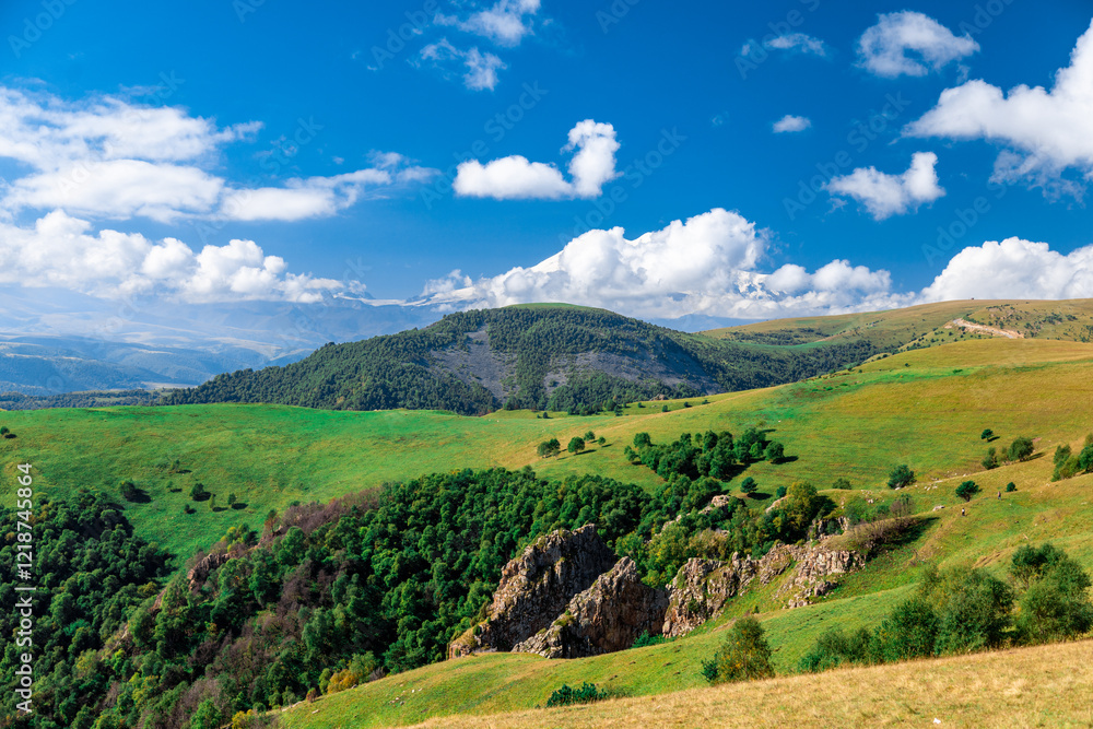 A mountain range with a lush green hillside. The sky is clear and blue. The mountains are covered in trees and the hillside is covered in grass A mountain range with a lush green hillside. The sky is clear and blue. The mountains are covered in trees and the hillside is covered in grass