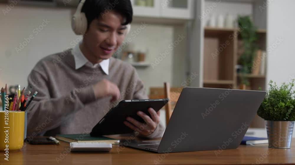 Smiling man in headphones taking notes, motivated interested male studying online, using tablet, watching webinar training or listening to lecture, remote education concept. Smiling man in headphones taking notes, motivated interested male studying online, using tablet, watching webinar training or listening to lecture, remote education concept.
