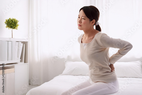腰痛に悩む30代～40代の女性。（A woman in her 30s or 40s suffering from lower back pain.）

