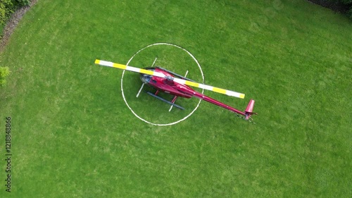 helicopter parked grass heliport vibrant red rotor blade unique perspective operational aspects circling downward aerial shot h pad drone aviation london scenic view travel air  photo