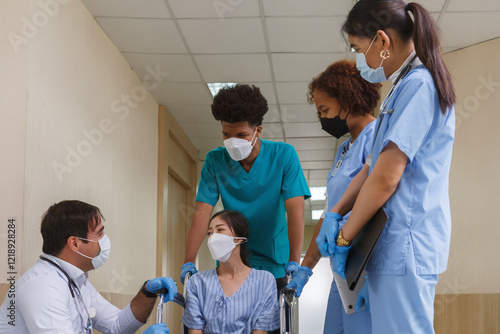 doctor and medical students team examining a patient in a wheelchair during a hospital consultation. Healthcare professionals wearing face masks and gloves for infection control. photo