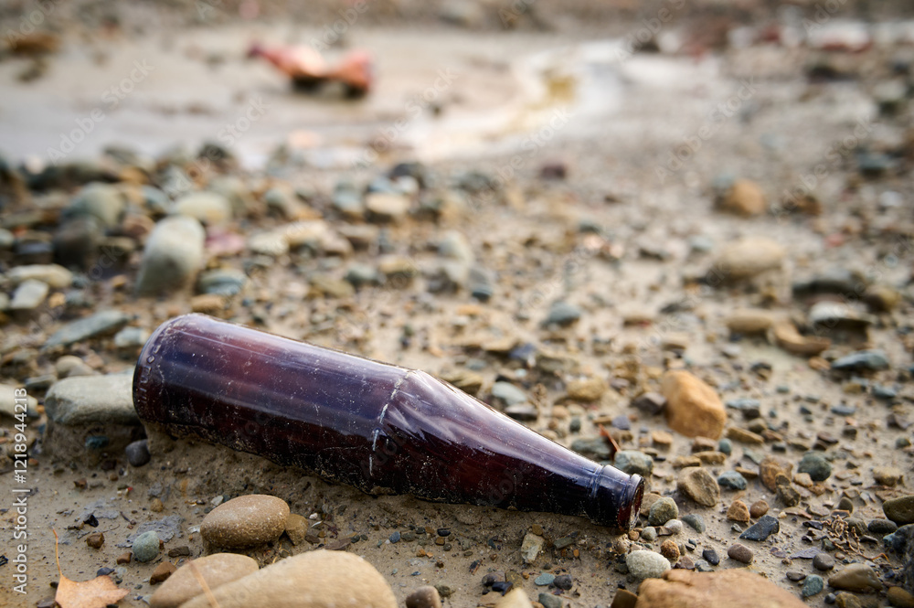 Brown glass bottle rests on a rocky shoreline after a heavy rainstorm at a seaside location