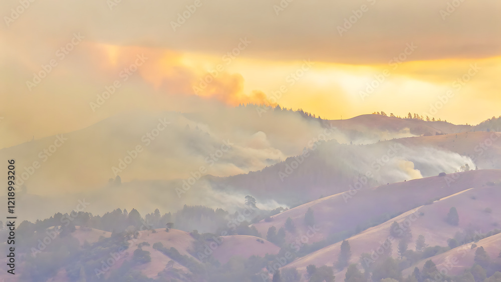Fototapeta premium A forest fire is raging in the mountains, with smoke and flames rising from the trees on the hillsides. An aerial view of nature in a dangerous condition during the summer season