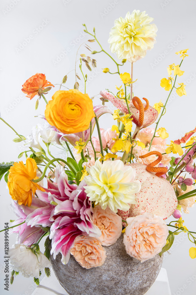 Obraz premium Cheerful floral arrangement with vibrant yellow dahlias, pink lilies, orange ranunculus, and pink roses, perfect for Valentine’s Day and Women’s Day