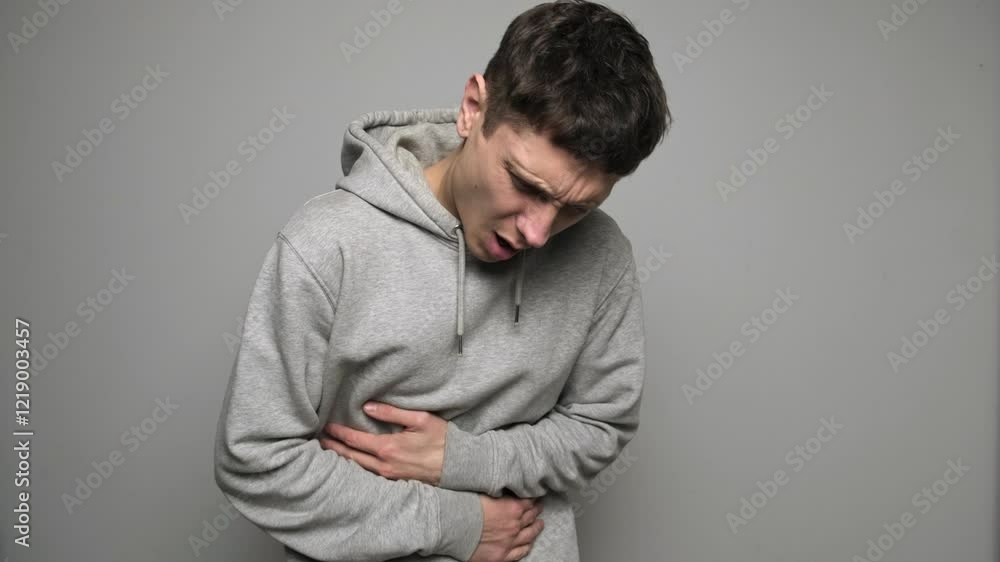 Man feeling sudden strong abdominal stomach ache, gastritis problem. Sick ill sad tired young man wear casual clothes put hands on abdomen suffering from stomach-ache griping bellyache. Man feeling sudden strong abdominal stomach ache, gastritis problem. Sick ill sad tired young man wear casual clothes put hands on abdomen suffering from stomach-ache griping bellyache.