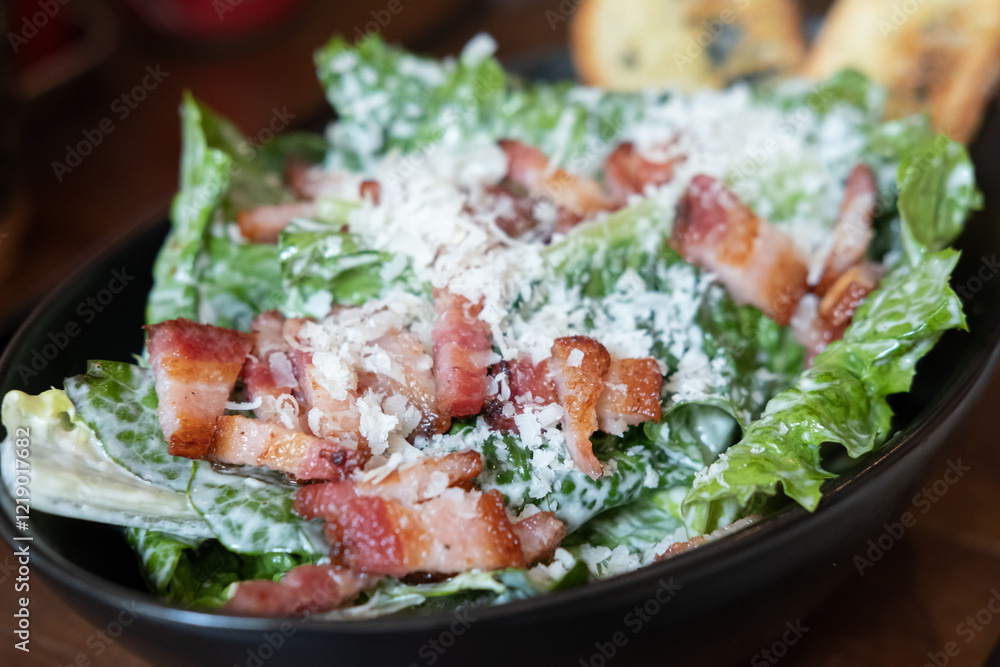 Salad with sliced bacon served in a bowl, on the table Salad with sliced bacon served in a bowl, on the table