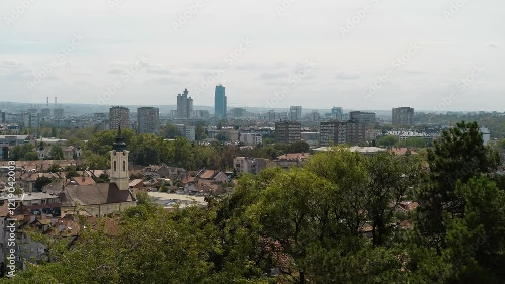 High angle view of townscape against sunny blue sky. View of the houses with red tiled roofs, the church and residential high-rise buildings. Zemun district in Belgrade, Serbia. Horizontal 4k footage High angle view of townscape against sunny blue sky. View of the houses with red tiled roofs, the church and residential high-rise buildings. Zemun district in Belgrade, Serbia. Horizontal 4k footage