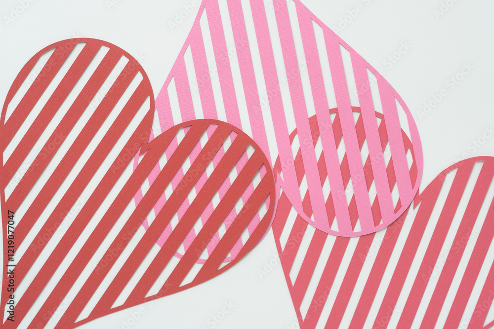 Obraz premium striped heart shapes machine-cut from pink and red crafting paper and arranged on blank paper