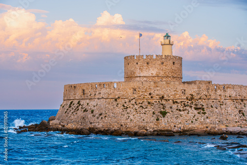 Medieval fortress of Saint Nicholas on the island of Rhodes at sunset. Picturesque landscape with blue sea, yachts and bright sky. Mediterranean atmosphere.
