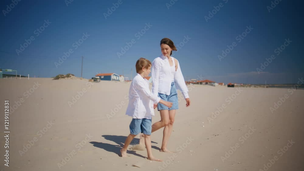 Smiling woman walking child on sandy beach. Mother enjoying time with cute son Smiling woman walking child on sandy beach. Mother enjoying time with cute son