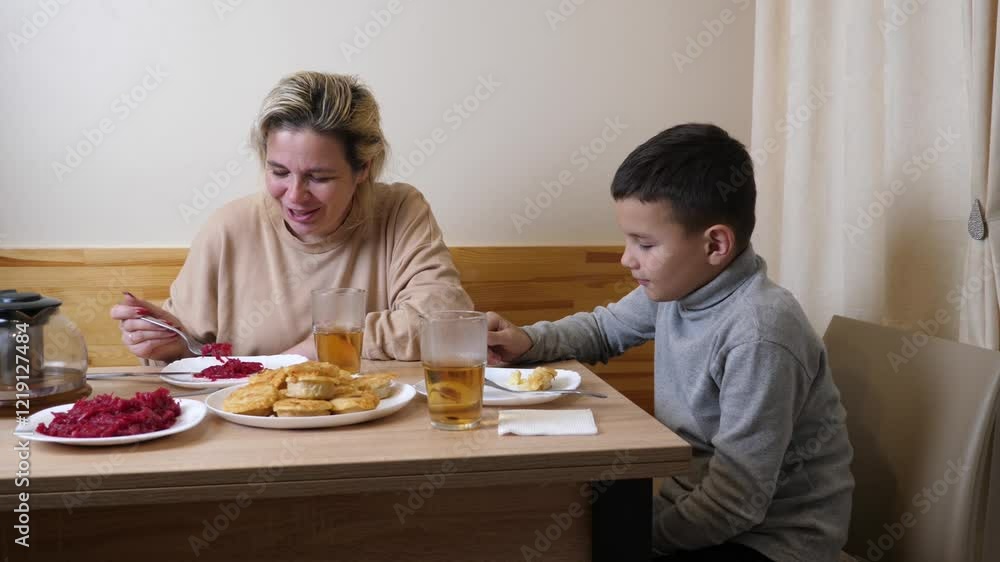Mother and son have dinner in the kitchen with homemade dishes. Mother and son have dinner in the kitchen with homemade dishes.