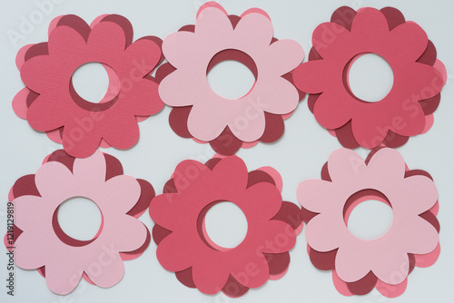 top-down view of six piles of machine-cut paper shapes with radial form (or petaled gears) on blank paper photo