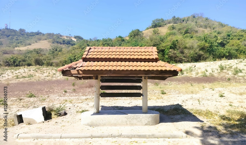 A small, traditional structure with a tiled roof sits in a serene landscape, surrounded by hills and greenery. A small, traditional structure with a tiled roof sits in a serene landscape, surrounded by hills and greenery.