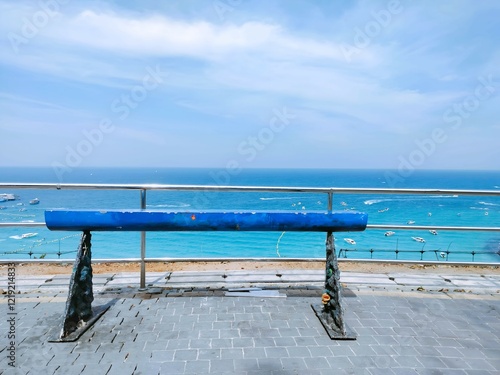 A blue balance beam overlooks a serene ocean view, framed by a clear sky and distant shore, creating a tranquil setting for practice or leisure.